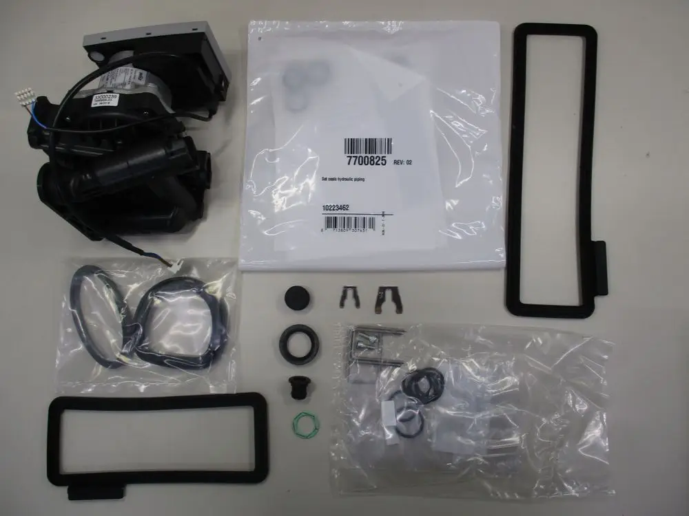 Remeha Hydroblock mit Pumpe, ergänzt durch verschiedene Dichtungen und Befestigungselemente, angeordnet auf hellem Tisch.